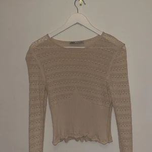 Beige spetsblus från Zara, M - Supersöt beige blus från Zara i storlek M. Blusen har långärmade ärmar, spetsmönster och ribbad nederdel med volangkant. Perfekt för dig som gillar romantisk och feminin stil. Sitter snyggt och är lätt att matcha med jeans eller kjol.