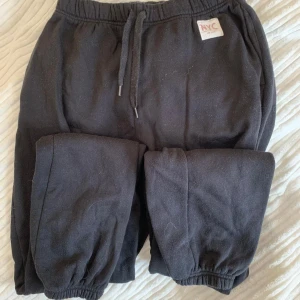 Svarta mjukisbyxor från H&M NYC - Svarta mjukisbyxor från H&M med NYC-detalj på höften. Byxorna har resår och snörning i midjan samt muddar vid bensluten. Dom är i fint skick men endast kanske lite noppig någonstans. Sitter kanske som storleken XS 