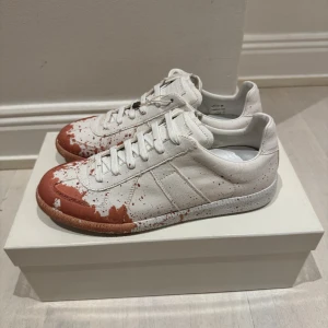 Maison Margiela sneakers paint splatter - Säljer dessa helt nya Maison Margiela sneakers i vitt med röd färgstänk över hela skon. Storlek 40. Allt medföljer. Hör av er vid frågor eller funderingar. 