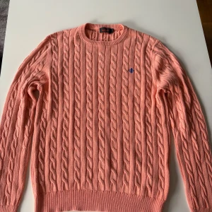 Rosa orange kabelstickad tröja Morris - Kabelstickad tröja från morris som är orange men lite rosa av sig också. Använd fåtal gånger. Inga defekter