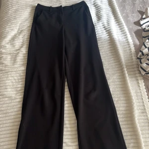 Svarta kostymbyxor med raka ben - Säljer ett par svarta kostymbyxor från Vero Moda. De har raka ben och en medelhög midja. De passar perfekt till Blus eller stickad tröja. De är i storlek XS. De har små tecken på användning och ett litet håll på ena knäet, dock inget som syns på håll 🥰