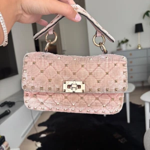 Rosa valentino spike bag  - Superfin rosa handväska från Valentino i  sammet med guldfärgade nitar. Väskan är missfärgad i färgen då den är så ljus vet ej om det går att kanske lämna in någon stans för tvätt annars bra skick, där av priset!