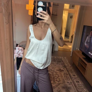 Vit siden-linnetopp med djup rygg - Säljer en stilren vit linnetopp i siden med djup urringning fram och snyggt djup rygg. Toppen är ärmlös och har en lös passform som ger en avslappnad men ändå chic vibe. Perfekt att matcha med jeans eller kjol för en clean look.