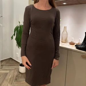 Brun långärmad klänning Chiara Forth - Snygg brun/grön långärmad klänning från Chiara Forth Milano. Modellen är figurnära med rund halsringning och slät design utan mönster. Perfekt för dig som gillar en stilren look. Materialet känns mjukt och följsamt mot kroppen. Säljer eftersom den är för stor för mig. (Har normalt sätt storlek M)