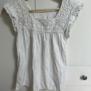 Vit blus med spetsdetaljer - Jättesöt somrig vit blus i stl xs. En fläck på en av ärmarna ellrr va man säger och sedan blev det ett hål i den som jag sydde igen mrn de syns inte eftersom det är längst ner på sidan.❣️❣️