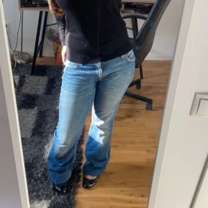 Blå bootcut jeans med låg midja - Säljer ett par snygga blå jeans med bootcut-modell och låg midja. Jeansen har klassisk femficksdesign och är tillverkade i mjukt denimtyg. Perfekta för dig som gillar en avslappnad och trendig look.