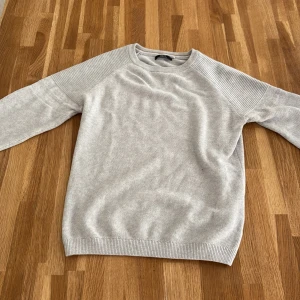 Ljusgrå stickad tröja från Next - Säljer en ljusgrå stickad tröja från Next. Tröjan har rund halsringning och långa ärmar med diskret ribbade muddar vid ärmslut och nederkant. Perfekt för lager-på-lager och enkel att matcha med olika outfits.