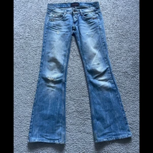 Lågmidjade bootcut jeans - Jätte fina jeans, lite slitna på ena benet (andra bilden). Mått: midjemått tvärsöver 38cm, grenhöjd 16cm, innerbenslängd 78cm🩷 sitter två jeansknappar, jag la till den andra eftersom de va aningen små runt höften🩷bra skick 🩷SKRIV FÖR FLER BILDER🩷kommer inte ta emot bud under 350