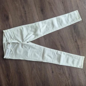 Vita skinny jeans från H&M - Säljer ett par vita skinny jeans från H&M med klassisk femficksdesign. Byxorna har dragkedja och knapp framtill samt smal passform hela vägen ner. Aldrig använd