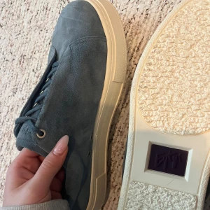 Blå sneakers i mocka med platt sula - Säljer ett par stilrena blå sneakers från eytys i mocka med vita platta sulor. Helt oanvända säljer billigt för att bli av med skor jag inte använder 
