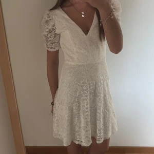 Vit spetsklänning från Bubbleroom - Säljer en superfin vit spetsklänning från Bubbleroom med v-ringning och puffärmar. Klänningen har kort längd och vackra spetsdetaljer över hela tyget. Perfekt för sommarens alla tillfällen! Använd endast 2 ggr! Köpte på bubbelroom men hittar inte den längre, köptes får ca 2år sedan, legat i garderoben tills nu.💕köptes för 799kr