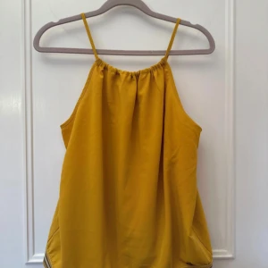 Gul linnetopp från Nümph - Säljer en solgul linnetopp från Nümph med smala axelband och glittrig gulddetalj längst ner. Toppen har en avslappnad passform och är perfekt för varma dagar ❤️❤️aldrig använd, fått som present❤️