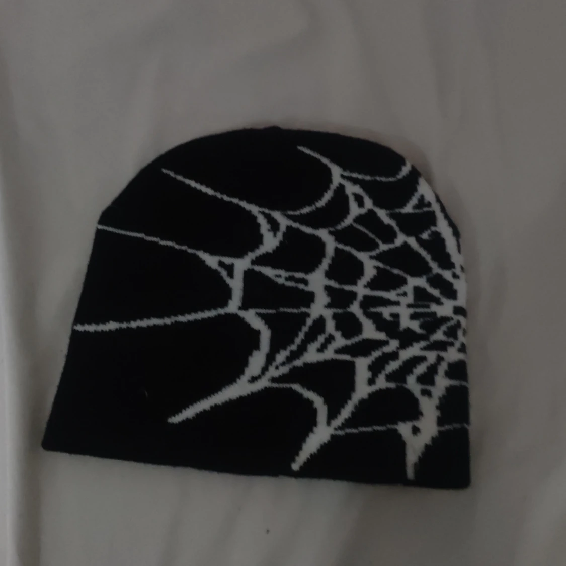 Svart mössa med spindelnätsmönster