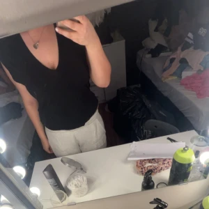 Svart v-ringad topp - Svart v-ringad topp med ärmlös design. Enkel och stilren modell som passar till många olika outfits. Perfekt för dig som gillar en klassisk look med modern touch.