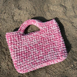 Virkad väska i rosa nyanser  - Superfin handväska i olika nyanser av rosa. Väskan har ett unikt mönster och kraftiga handtag, perfekt för att lyfta vilken outfit som helst. Den är både söt och trendig, och passar dig som vill sticka ut lite extra. Kika gärna in vår Instagram @design.by.bela för andra modeller och väskor. 