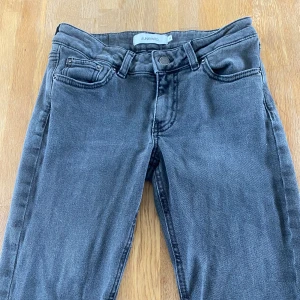 Grå jeansbyxor från Junkyard - Snygga grå jeansbyxor från Junkyard med klassisk femficksdesign och bootcut. Byxorna har normal passform och är endast andvänd 1 gång på grund av för stor storlek för mig. Köparen står för frakt!