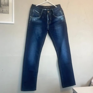 Mörkblåa jeans från  LONG LI JEANS - Ett fint par nya mans jeans från LONG LI JEANS. Fina vita stygn med unika detaljer. Jeansen är även whitewashed. Populära fashion byxor!