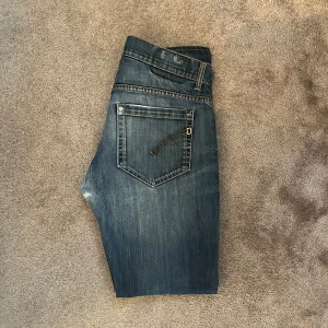 Blå Dondup jeans med slitningar - Snygga blå jeans med en cool slitning på framsidan. De är i bra skick men använda skulle säga 8/10 skick. Sitter ganska slimmat och priset är ej hugget i sten.