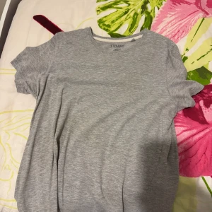 Ljusgrå basic t-shirt från Livergy - En enkel och stilren ljusgrå t-shirt från Livergy. T-shirten har rund halsringning och korta ärmar. Perfekt att matcha med jeans eller shorts för en avslappnad look.