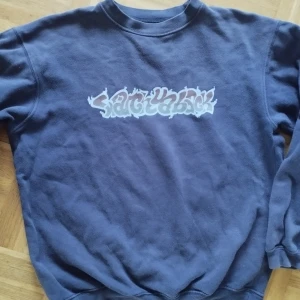 Mörkblå sweatshirt från Red Roc - Säljer en mörkblå sweatshirt från Red Roc med tryck i graffiti-stil på bröstet. Tröjan är i 100% bomull och har en klassisk rund hals och långa ärmar. Perfekt för en avslappnad och cool stil. Från tidigt tvåtusental. Strl xl youth så typ M.