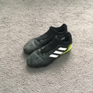 Adidas Copa fotbollsskor i svart och neon - Säljer ett par Adidas Copa fotbollsskor i svart med vita ränder och neonfärgade detaljer på hälen och sulan. Skorna har låg profil, rund tå och är tillverkade i skinn. Perfekta för dig som vill sticka ut på planen. !!! Saknar sko snöre !!!