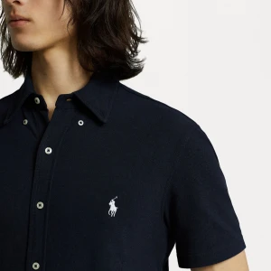 Mörkblå kortärmad skjorta från Polo Ralph Lauren - Snygg mörkblå skjorta från Polo Ralph Lauren med korta ärmar och klassisk krage. Skjortan har vita knappar och den ikoniska broderade loggan på bröstet. Perfekt för en stilren och avslappnad look.Helt ny, använt ungefär 2-3 ggr