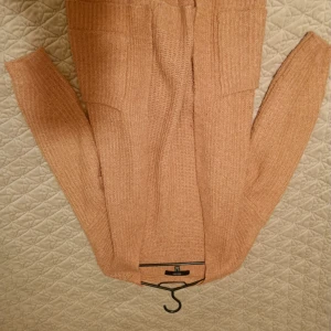 Beige stickad kofta med bälte - Mysig beige stickad kofta från Gina Tricot med långa ärmar och knytskärp i midjan. Perfekt för lager-på-lager och enkel att styla till olika outfits. Snygg ribbad struktur och två fickor framtill.