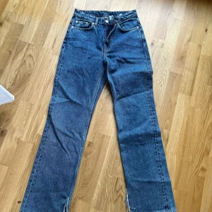 Voyage jeans från Weekday - Säljer ett par klassiska blå jeans från Weekday med raka ben och hög midja. Jeansen har fem fickor, gylf med dragkedja och knapp samt tydliga sömmar. Perfekta för en avslappnad och stilren look. Weekday model Voyage i mellanblå, klippt slits på insidan av benen! 