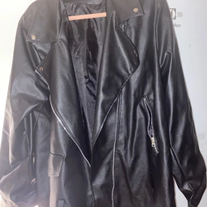 Svart skinnjacka med dragkedja - Säljer en svart skinnjacka med klassisk bikerstil. Jackan har breda slag, sned dragkedja och fickor med dragkedjor. Perfekt för dig som vill ha en cool och tidlös look. Jackan är endast testad och inte använd. Kan användas av många storlekar som oversize eller regular fit, allt mellan M-XL