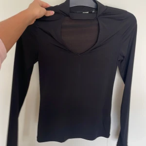 Svart långärmad topp med v-ringning från Bikbok - Säljer en svart långärmad topp från Bikbok med snygg v-ringning och åtsittande passform. Perfekt att styla med jeans eller kjol för en trendig look.