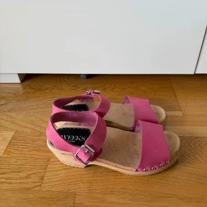 Sweeks of Sweden sandaler i nyskick. 38. Skinn - •Modern träsko i cerisefärgat skinn på en lägre klack som ger en trendig känsla och skön komfort.  •Spänne i silver. •Klackhöjd: 4,5 cm •Material: Skinn •Djurfritt och rökfritt hem