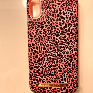 Leopardmönstrat mobilskal från iDeal of Sweden - Säljer ett snyggt mobilskal från iDeal of Sweden med rosa och svarta leopardmönster. Skalets baksida har en guldfärgad logga.