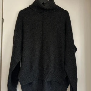 Mörkgrå stickad polotröja från H&M - Säljer en mörkgrå stickad polotröja från H&M. Tröjan har en hög polokrage, lång ärm och avslappnad passform . Perfekt för kyliga dagar! Oversized