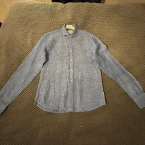 Blå skjorta från Scotch & Soda - Snygg blå långärmad skjorta från Scotch & Soda. Tillverkad i ett lätt och bekvämt material, perfekt för både vardag och mer uppklädda tillfällen. Skjortan har klassisk krage och knappar framtill.