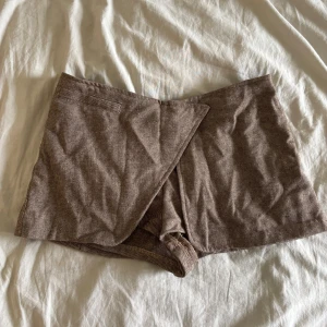 Brun shortskjol  - Säljer en brun shortskjol med snygg omlottdesign framtill och dolda tryckknappar. Perfekta för sommaren och ger en trendig look 😍 aldrig använt 