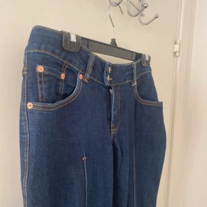Mörkblå bootcut jeans med låg midja - Säljer ett par mörkblå jeans med bootcut passform och låg midja. Byxorna har klassiska fem fickor, synliga sömmar och stängs med dragkedja och dubbla knappar. Köpt på Lager 157 i storleken Tall! Aldrig använd! 