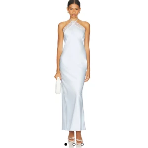 Libbie Gown in Light Blue MAJORELLE - Använd en gång, inga defekter. 100 % polyester. Tillverkad i Kina. Endast kemtvätt. Ofodrad. Dold dragkedja baktill med halterneck-knytning. Satintyg med spetskant och sprund bak. Revolve modellnummer MALR-WD1421. Tillverkarmodellnummer MJD1143 U24.