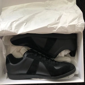 Maison Margiela Sneakers - Säljer ett par super snygga gatts ( Maison Margiela) skor, super trendiga och sköna. Jag säljer dem då det inte passar min storlek. Hör av er om ni vill byta till något annat, eller om ni har några frågar samt prisförslag! Inkluderar box, 2 dustbags (billigare pris därav att jag råkat skadat boxen lite)