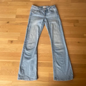 Ljusblå bootcut jeans från Gina Tricot - Säljer ett par ljusblå lågmidjade bootcut jeans från Gina Young i storlek 158 i mycket bra skick. Jeansen har klassiska fem fickor, knapp och dragkedja framtill samt snygga detaljer på bakfickorna. Perfekta för dig som gillar en lite vidare passform nertill.