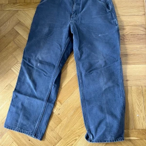 Grå cargobyxor från Carhartt - Säljer ett par grå cargobyxor från Carhartt i 100% bomull. Byxorna har flera praktiska fickor både fram och bak samt en loose passform. Perfekta för dig som gillar en avslappnad stil och vill ha slitstarka byxor.
