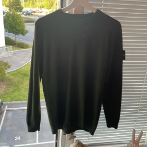 Mörkgrön stickad tröja från Stone Island - Säljer en mörkgrön stickad tröja från Stone Island med klassisk patch på vänster ärm. Tröjan har rund halsringning och långa ärmar med ribbade muddar. Perfekt för dig som gillar stilrena och snygga plagg med streetkänsla, tröjan i sig sitter tight så för dig som vill visa sina gym gains är den perfekt, pris kan självklart diskuteras 