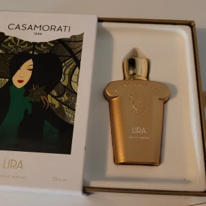 Casamorati Lira Eau de Parfum 30ml-ny - Casamorati Lira är en lyxig parfym i en elegant guldig flaska på 30 ml. Doften har inslag av karamell, citrus, lavendel, kanel och lakrits, med en varm och söt bas av vanilj, blodapelsin och egyptisk jasmin. Förpackningen har en stilren art nouveau-design med guldiga detaljer.