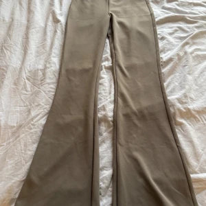 Beiga byxor med utsvängda ben från H&M XS - Snygga beiga byxor från H&M i storlek XS. Byxorna har en mjuk och stretchig känsla, med utsvängda ben och en clean look utan synliga detaljer. Perfekta för dig som gillar en trendig och stilren vibe. Helt oanvända.