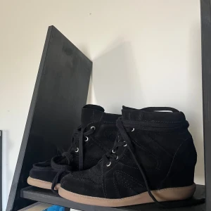 Svarta boots från Pavement - HELT NYA, ALDRIG ANVÄNDA. Svarta sneakers från Pavement i mocka med kilklack och snörning. Skorna har en beige gummisula och detaljerade sömmar som ger en cool look. Perfekta för dig som vill ha lite extra höjd men ändå känna dig bekväm.