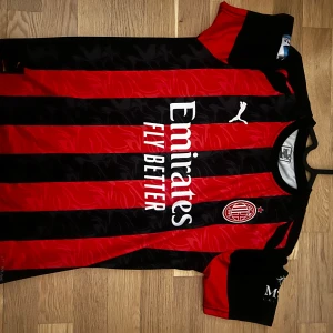AC Milan 25/26 Hemmatröja - Luka Modric’ #14 fotbollströja - Säljer en svart/röd AC Milan hemmatröja med Modric och nummer 14 på ryggen. Tröjan har klassiska röda och svarta vertikala ränder, korta ärmar och flera sponsorer tryckta på bröst och ärm. Den är i väldigt bra skick och har bara använts ett par gånger under sommarn. Kan skickas omgående! Tveka inte att höra av er för mer information/bilder om tröjan 🌟