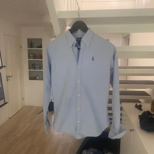Ljusblå skjorta från Ralph Lauren  - Snygg ljusblå skjorta från Ralph Lauren i slim fit-modell. Sitter extremt bra och är en steal för pengarna. Nypris är 1500 och den är knappt använd.