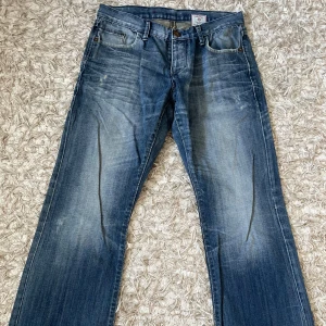 Blå jeans från Jack & Jones - Snygga blå jeans från Jack & Jones med klassisk femficksdesign och slitna detaljer framtill och baktill. Jeansen har raka ben och coola sömmar på bakfickorna. Perfekta till en avslappnad streetstil.