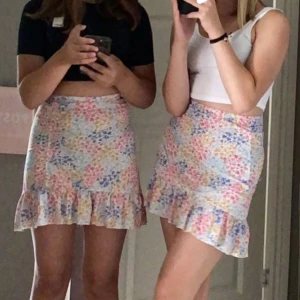 Blommig volangkjol i pastellfärger - Supersöt kort kjol med blommigt mönster i ljusa pastellfärger. Kjolen har volang nertill och sitter snyggt i midjan. Storlek xs. Använd ett fåtal gånger💗 