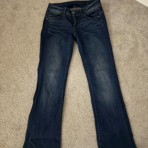 G-Star RAW Midge Bootcut Jeans - Snygga mörkblå bootcut jeans från G-Star RAW, modell Midge. Klassisk femficksdesign med G-Star-logga på myntfickan och kontrastsömmar. Jeansen är i stretchigt denim och har en normal passform med bootcut-ben. Perfekta till sneakers eller boots. Det är längd 34 men dom är upplagda till längd 32. Köpte dom för 1200.