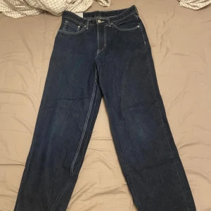 Loose fit jeans från H&M, blå - Säljer ett par mörkblå jeans från H&M i loose fit-modell. Klassisk femficksdesign med vita kontrastsömmar och raka ben. Jeansen har normal midja och är tillverkade i jeansmaterial. Perfekt för dig som gillar avslappnad stil.